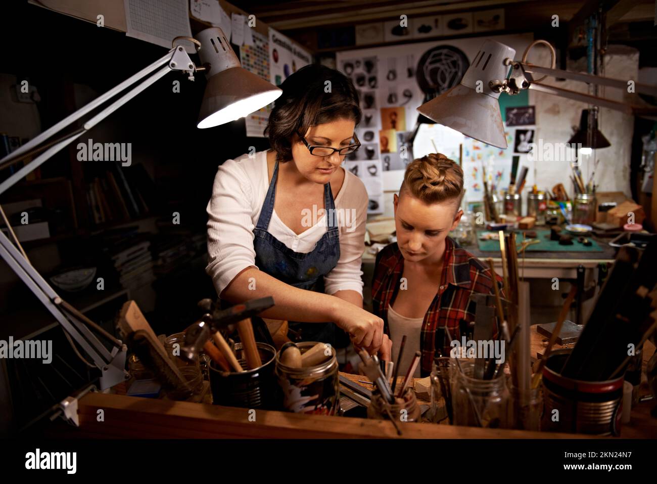 Aider un collègue de travail. deux jeunes femmes travaillant ensemble sur des objets artisanaux. Banque D'Images
