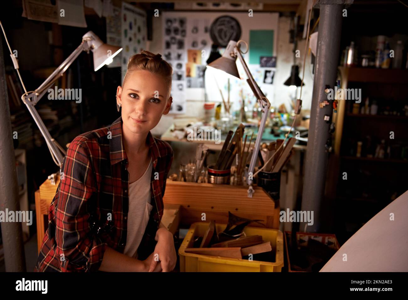 Heureux dans son propre espace de travail. une belle jeune femme assise dans un atelier. Banque D'Images