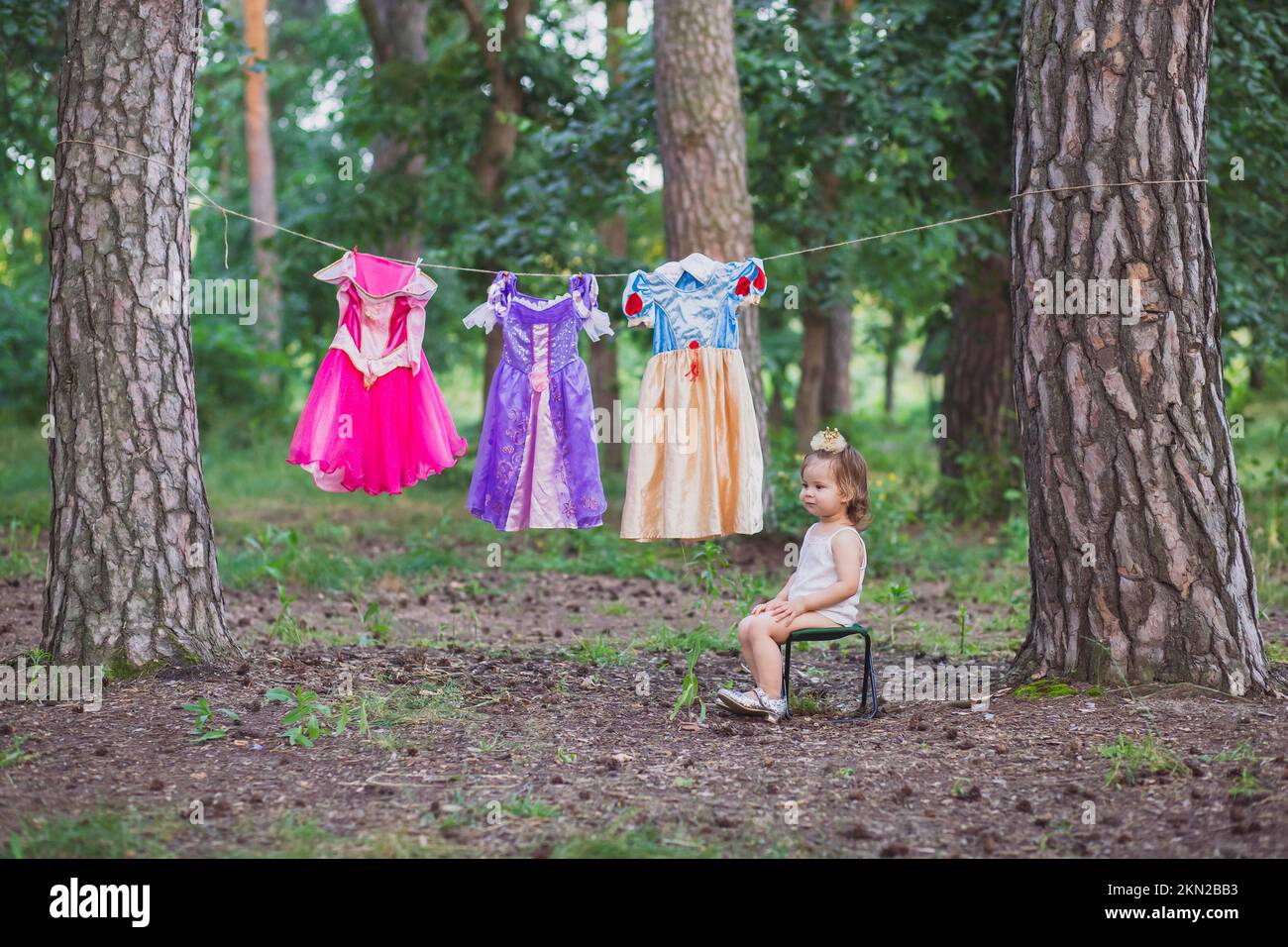Bébé charmant a suspendu des costumes de princesse pour sécher Banque D'Images