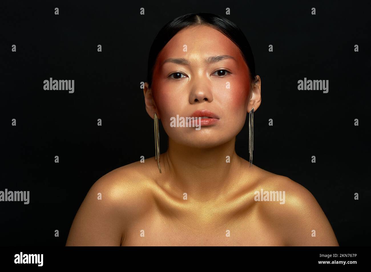Une fille asiatique sur fond noir dans le studio. Or. Portrait dans les salons de beauté. Banque D'Images