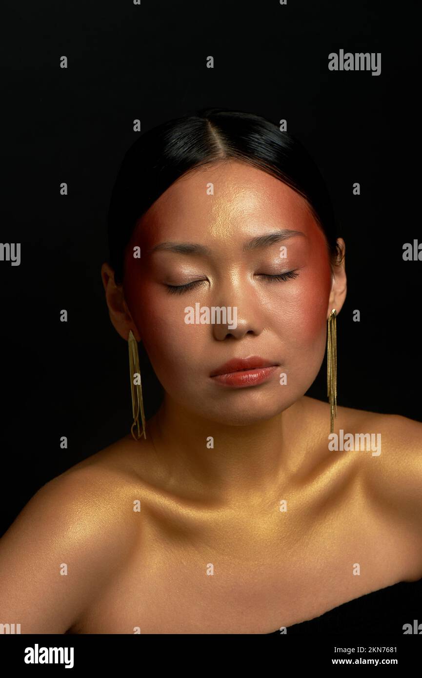 Une fille asiatique sur fond noir dans le studio. Or. L'émotion de la paix Banque D'Images