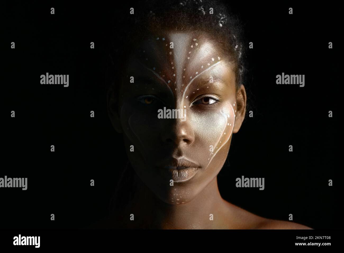 Portrait d'une belle fille africaine avec des peintures tribales traditionnelles sur son visage sur fond noir Banque D'Images