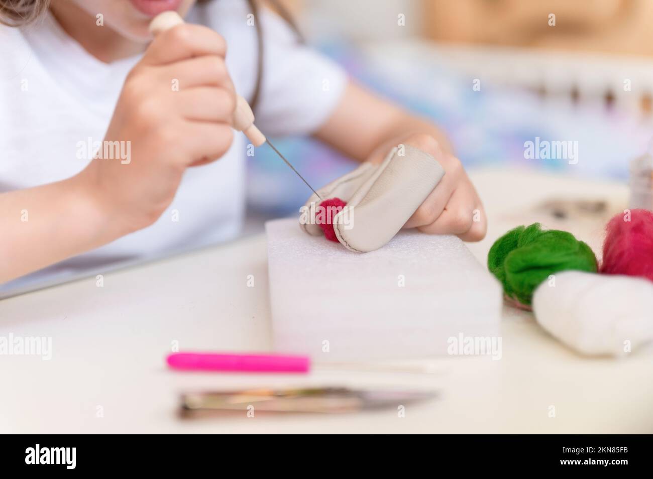 laine de feutre fabriquée à la main avec aiguille. petite fille artisan jeune fille de neuf ans avec la main fait un jouet créatif fait de cheveux de mouton. personnes plaque de cuisson pour enfants Banque D'Images