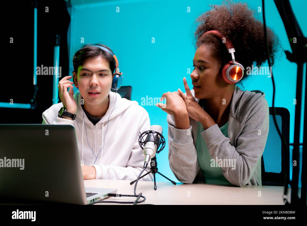 Jeune femme afro-américaine et homme asiatique un podcast interview et conversation ensemble en studio, homme et femme hôte portant casque parler avec Banque D'Images