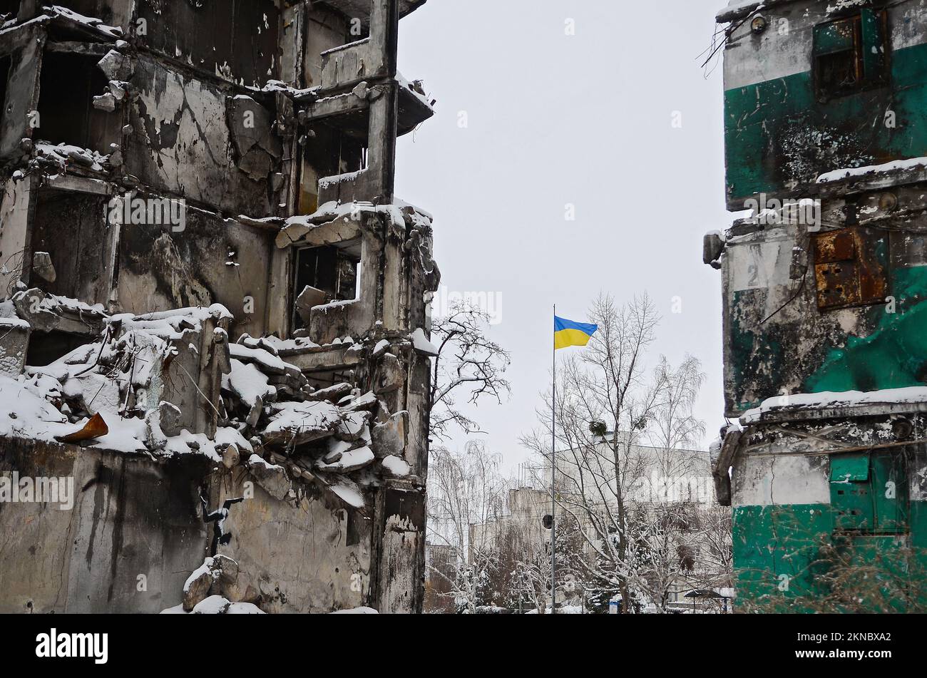 BORODIANKA, UKRAINE - 22 NOVEMBRE 2022 - Un drapeau ukrainien vole sur le poteau près des ruines d'un immeuble d'appartements détruit par les troupes russes où Banque D'Images