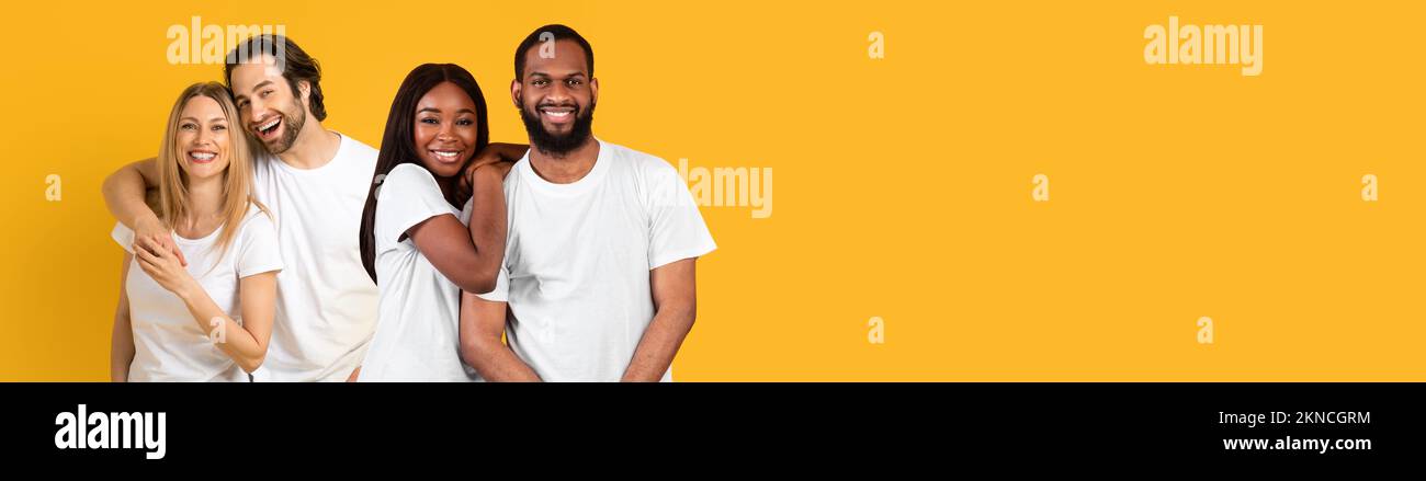 Les jeunes couples heureux blancs et noirs s'embrassent sur le jaune Banque D'Images