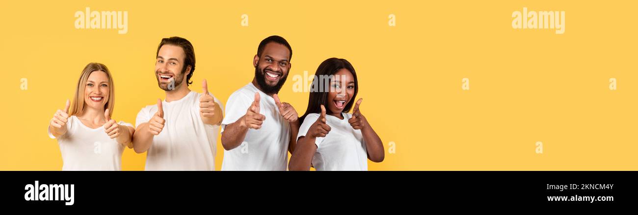 Jeunes couples heureux blancs et noirs montrant des pouces Banque D'Images