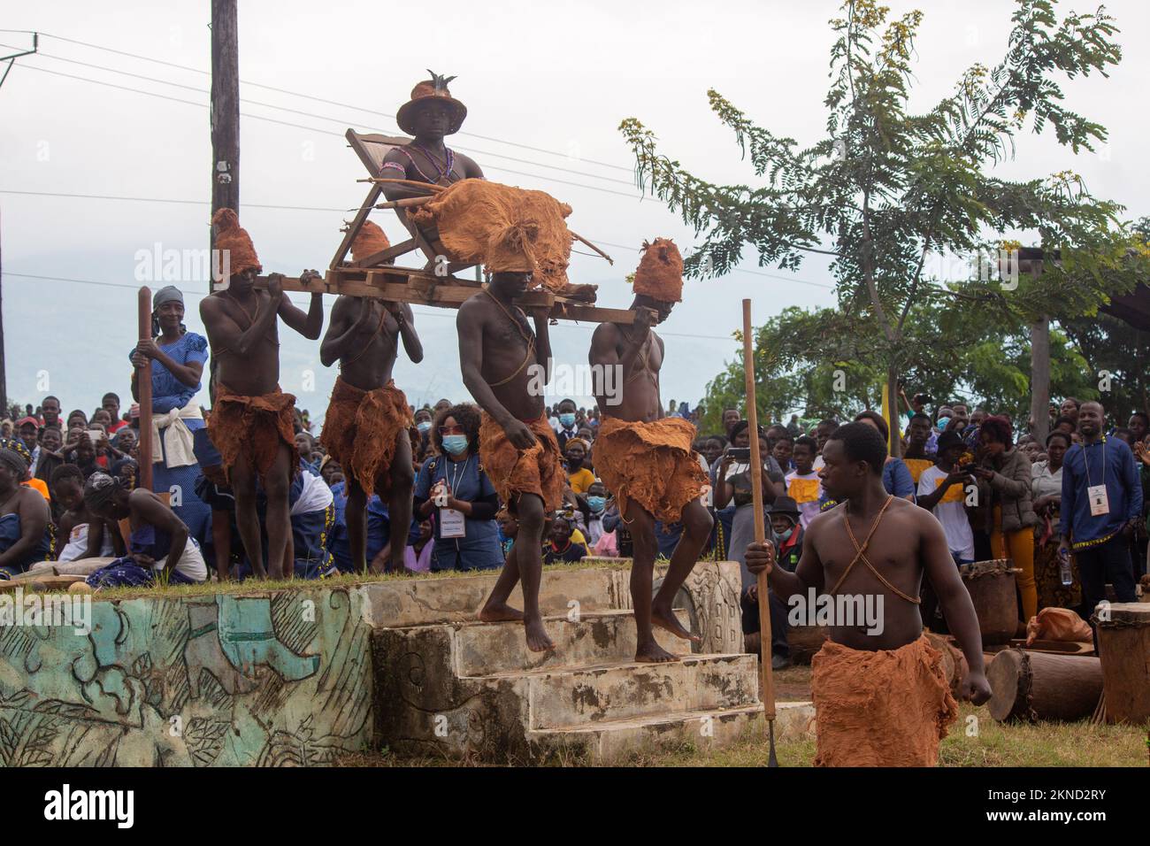 Les hommes montrent comment les serviteurs portaient la litière contenant leur roi africain, portant des vêtements traditionnels de peau d'animal Banque D'Images