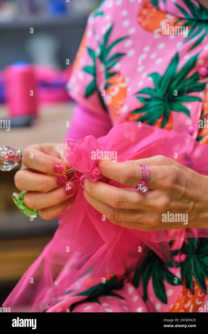 Tailleur inreconnaissable avec des vêtements colorés couture à la main d'un morceau de tissu. Banque D'Images