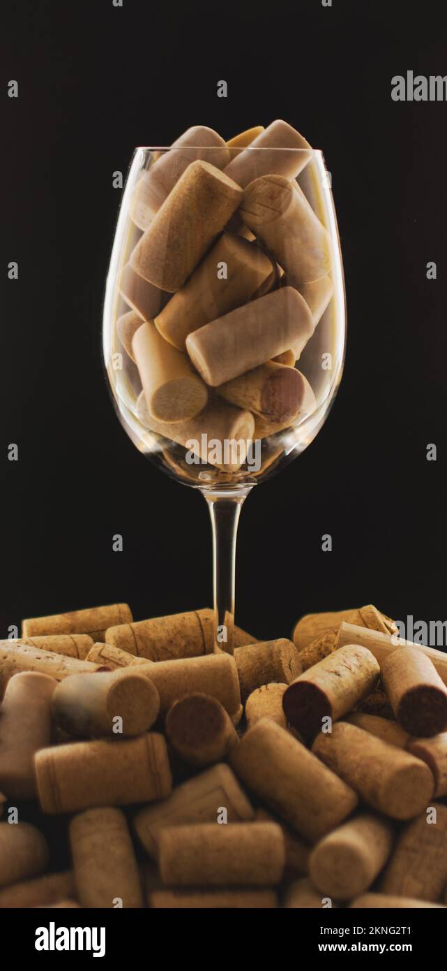 verre à vin plein de bouchons en liège sur fond noir sur une base de bouchons en liège empilés Banque D'Images