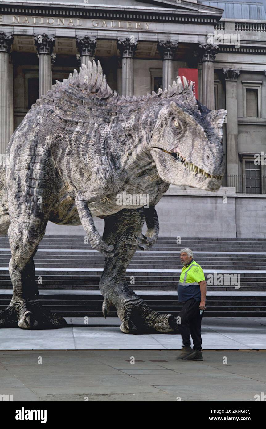 Workman marchant devant Un grand écran avec Une image projetée d'Un T-Rex à l'extérieur de la National Gallery, Londres Royaume-Uni Banque D'Images