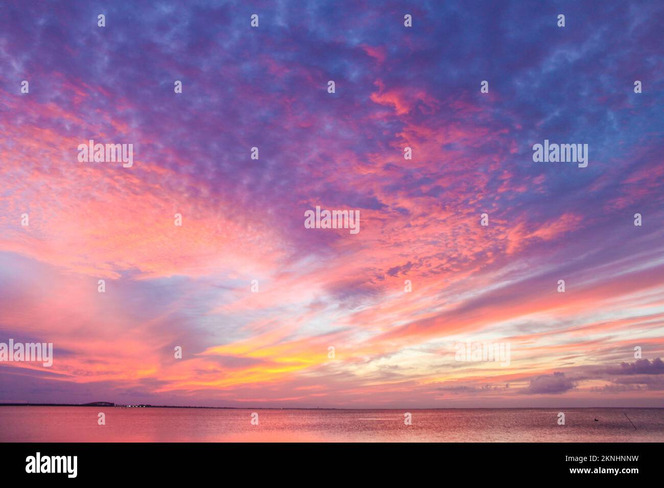 Magnifique coucher de soleil coloré avec des couleurs qui s'envolent de l'horizon au-dessus de l'océan avec des couleurs jaune et rose débordant de pourpre aux cheveux près du sommet Banque D'Images