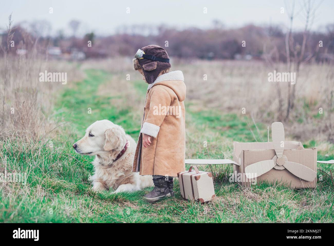 Charmant bébé triste dans les vêtements de l'aviateur dit Au revoir au chien Banque D'Images