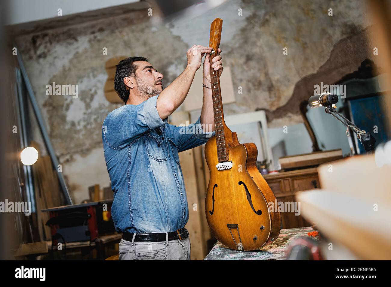 Luthier artisan fixation d'une guitare vissant la barre de treillis dans son studio-garage vintage - musique, art, artisanat et gens style de vie concept Banque D'Images