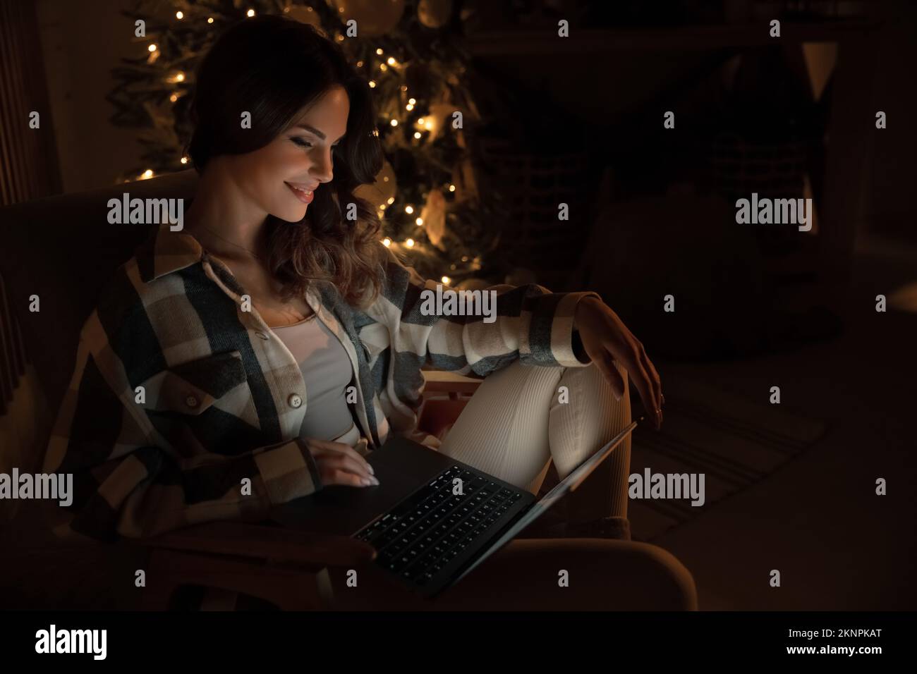 Belle femme utilisant un ordinateur portable et Internet sur le canapé à Noël. Réseau social. Concept de vacances Banque D'Images