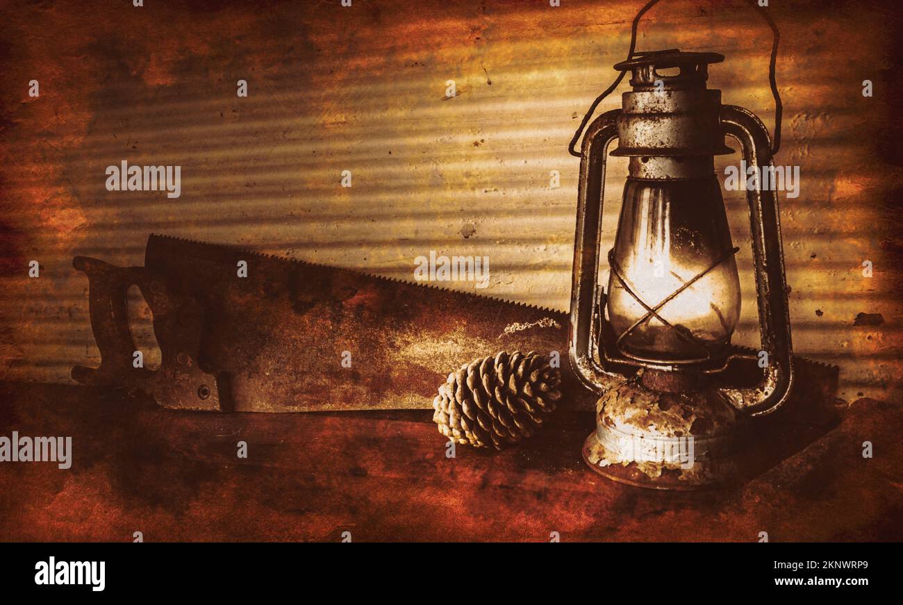 Photo d'époque encore en vie sur une lanterne brûlante à l'huile de kérosène lampe à côté de la pomme de pin et de la scie antique rouille dans le pays rustique grange avec plancher en bois vieilli Banque D'Images