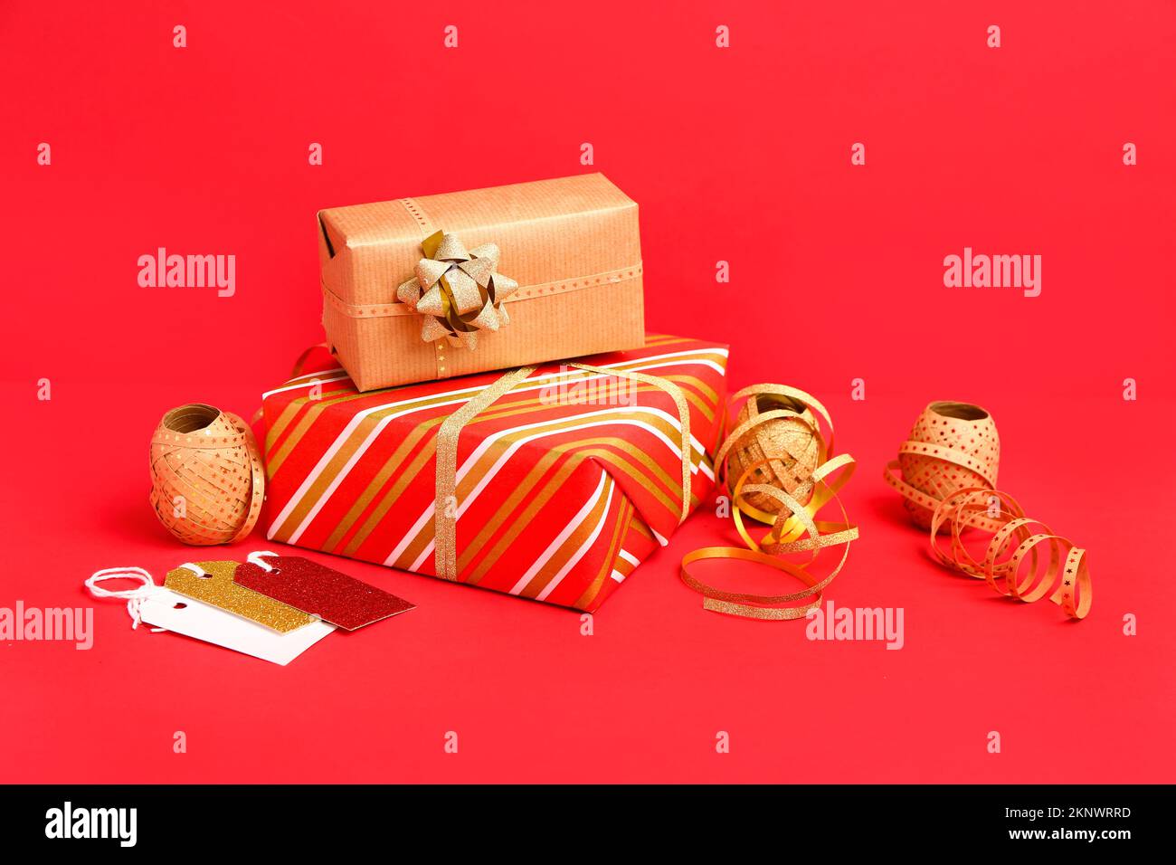 Composition avec cadeau de Noël et matériaux d'emballage sur fond rouge Banque D'Images
