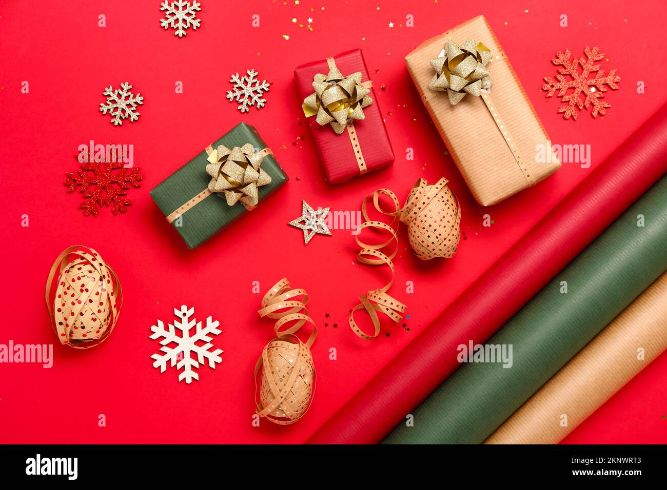 Composition avec cadeaux de Noël, décorations et matériaux d'emballage sur fond rouge Banque D'Images