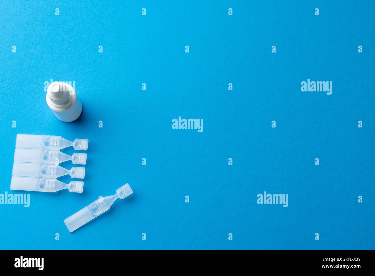Tête de caplets de solution saline et flacon compte-gouttes sur fond bleu avec espace de copie Banque D'Images
