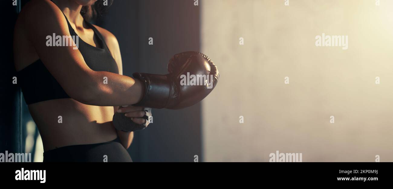 Une jeune femme en gros plan porte un gant de boxe dans la salle de sport. Banque D'Images