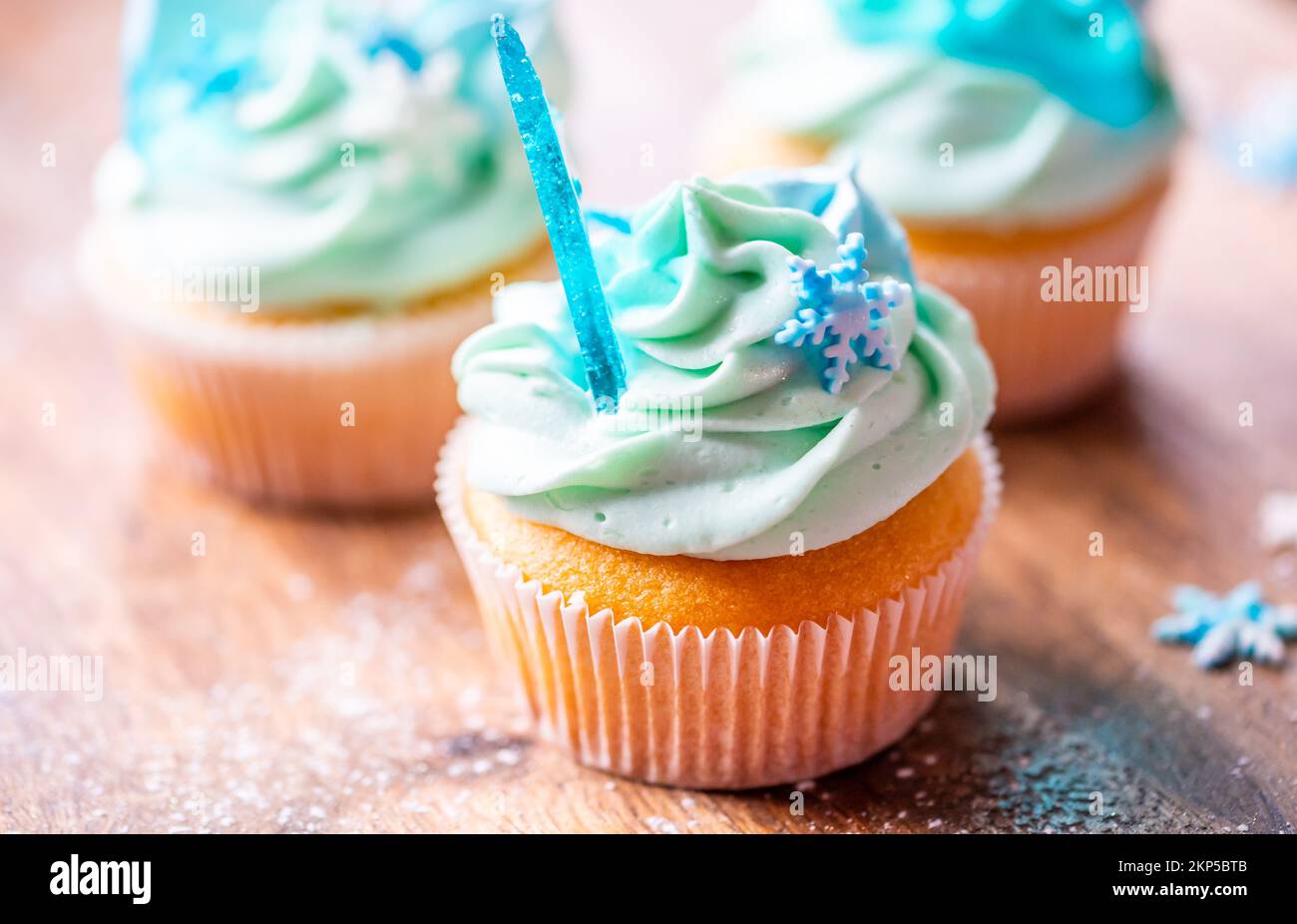 Un petit gâteau fait maison de couleur bleue placé sur un bureau en bois. Thème hiver et noël, flocons de neige sur crème avec glace bleue. Doux frais et maison. Banque D'Images