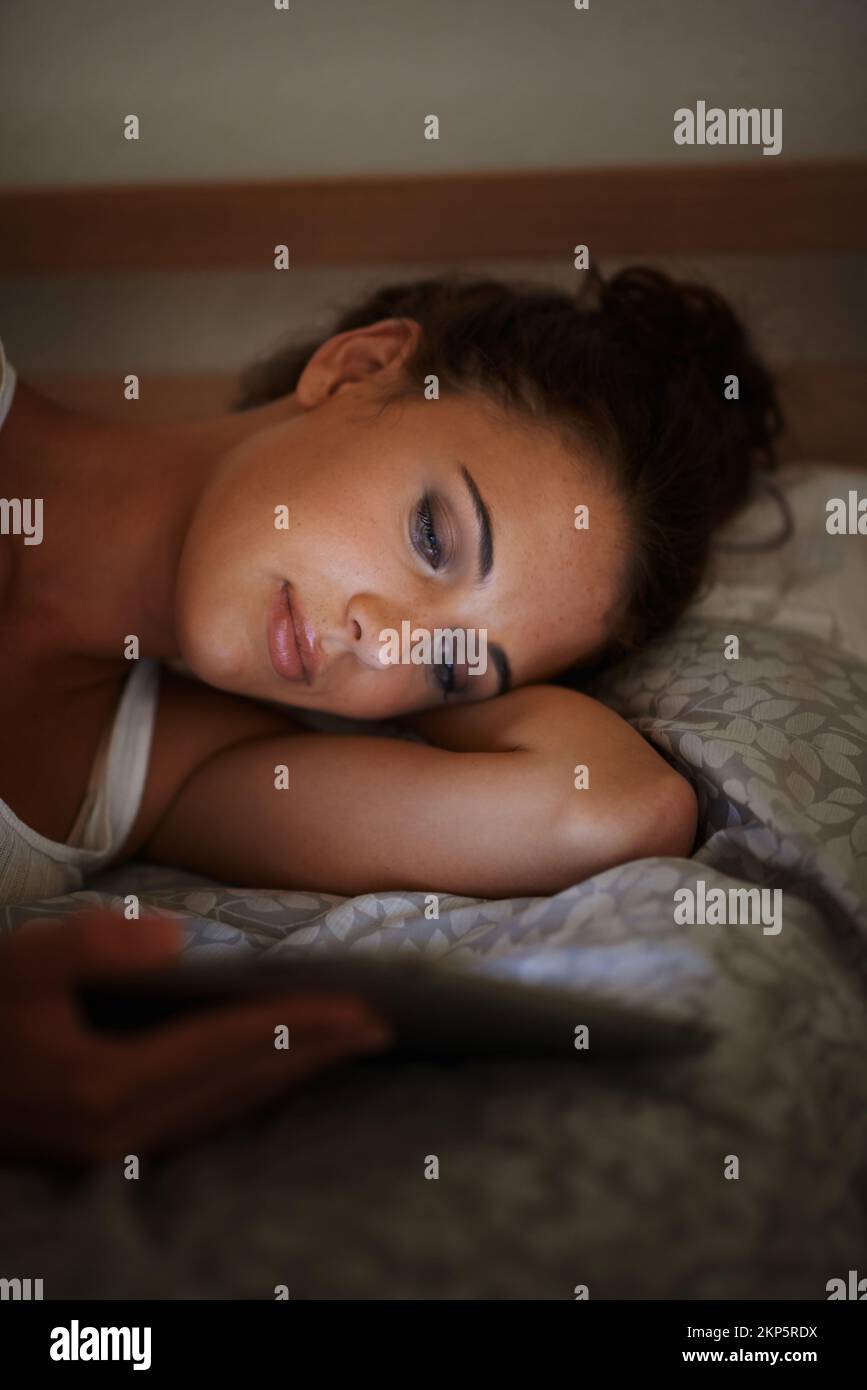 Navigation au coucher. une jeune femme attrayante utilisant sa tablette dans le lit. Banque D'Images