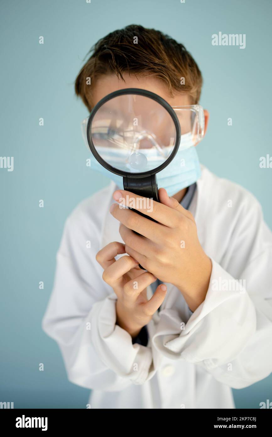 cool drôle bub habillé comme scientifique avec une grande loupe et des verres noirs devant le fond bleu Banque D'Images