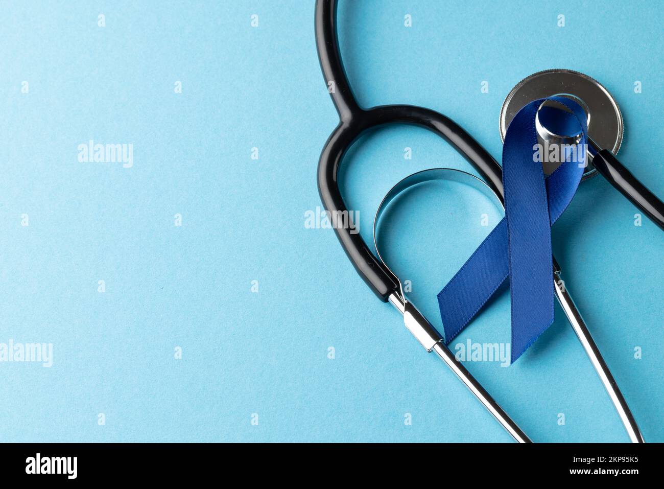 Composition d'un ruban bleu de sensibilisation au cancer et d'un stéthoscope sur fond bleu avec espace de copie Banque D'Images