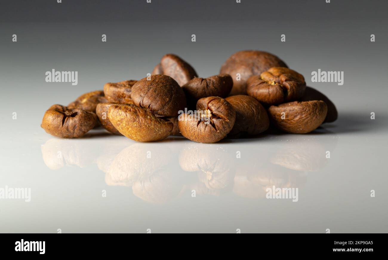 Pile de grains de café bruns sur fond de table blanc Banque D'Images