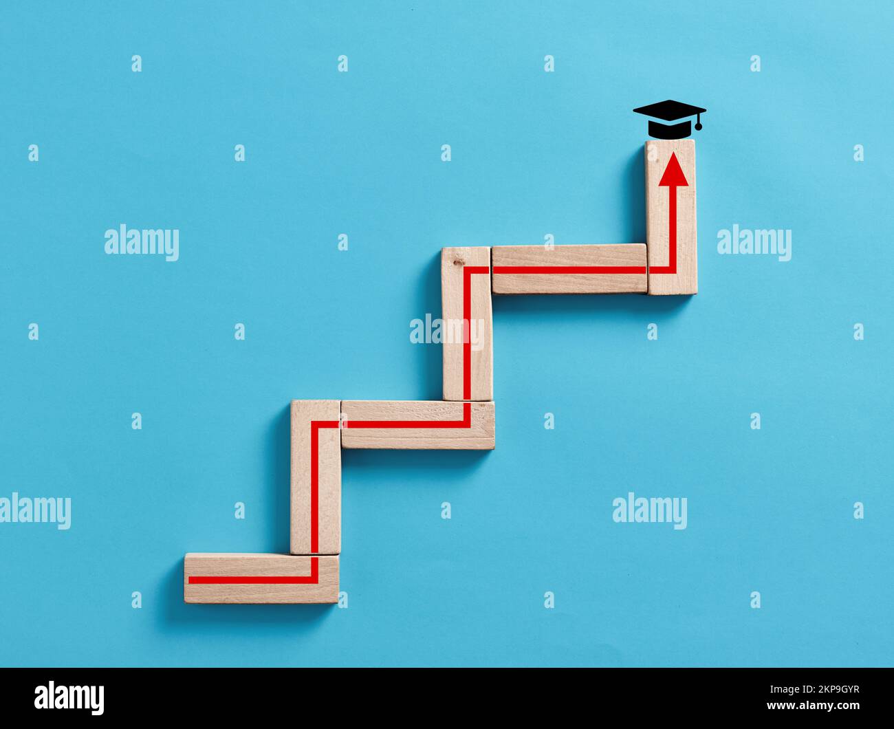 Obtenir un diplôme, un diplôme et un diplôme en éducation concept. Blocs en bois empilés comme un escalier avec une flèche ascendante avec symbole de capuchon de graduation Banque D'Images