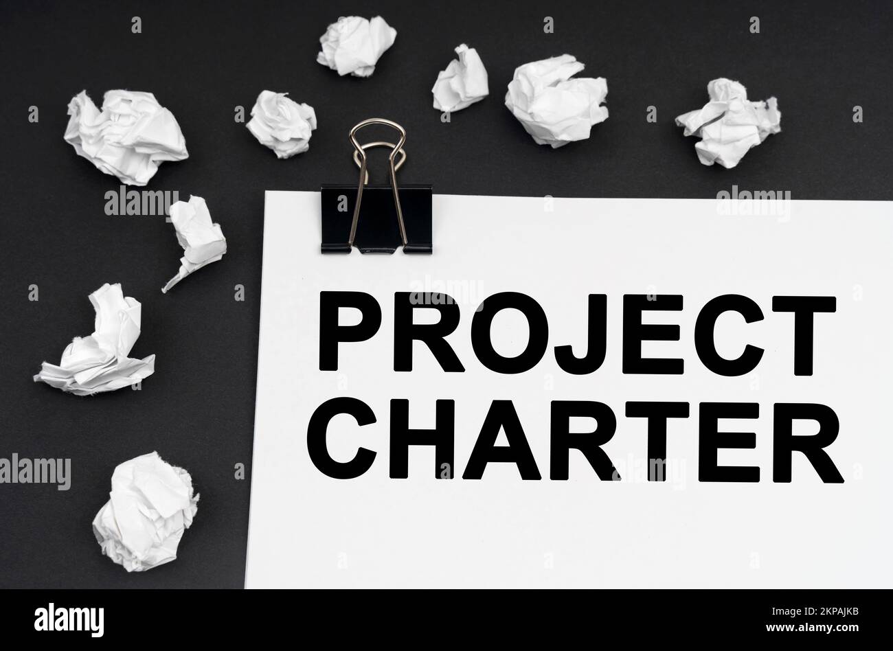 Concept industriel. Sur fond noir, il y a des morceaux de papier et de papier émiettés avec l'inscription - Charte du projet Banque D'Images