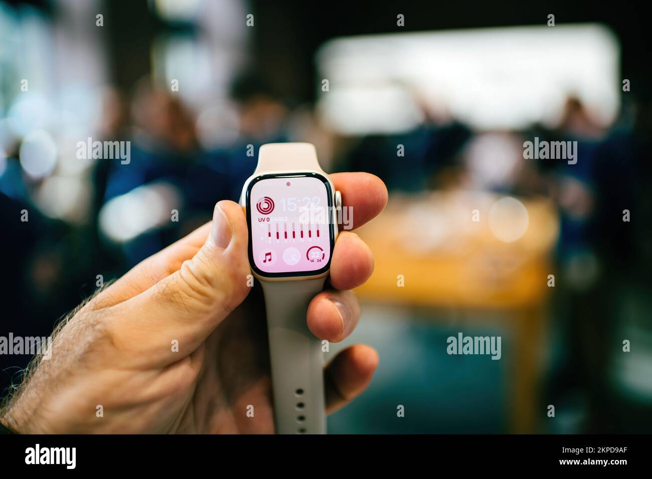 Paris, France - 28 octobre 2022 : main mâle POV tenant la dernière montre Apple Watch Series 8 LTE avec des clients désamorcés en arrière-plan Banque D'Images