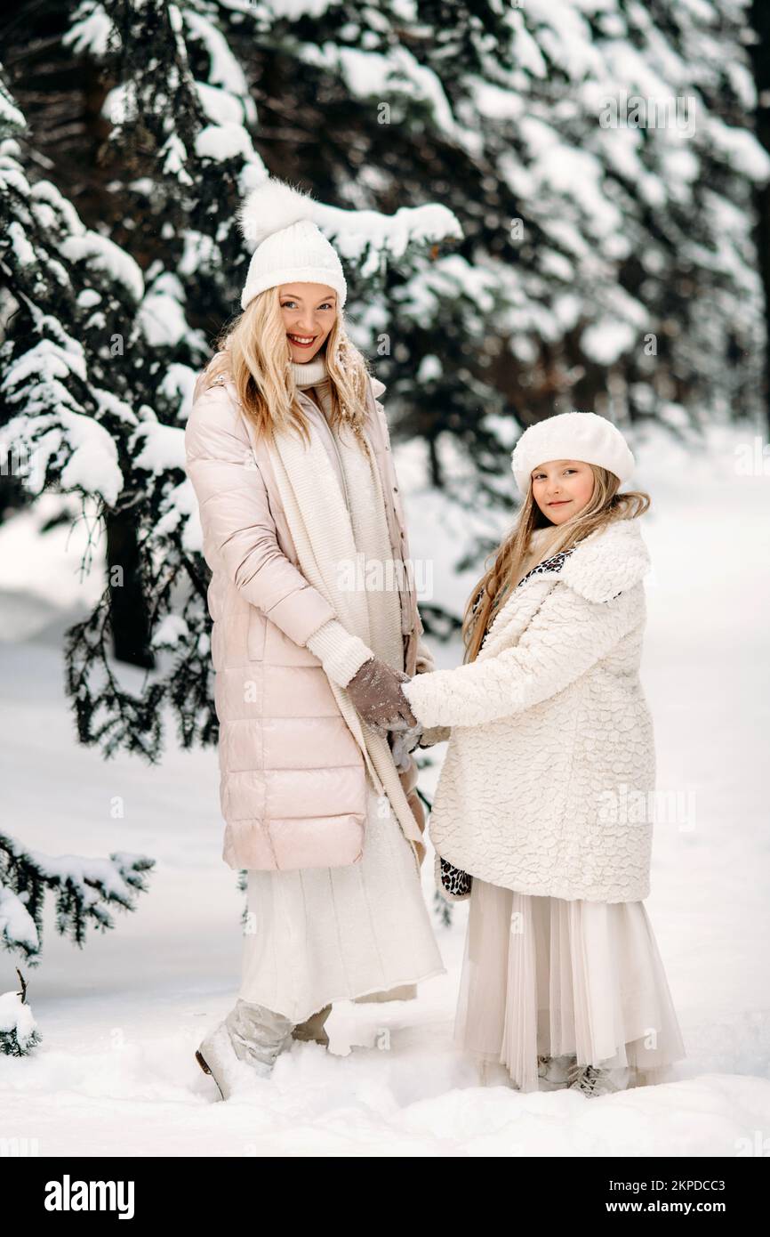 Belle mère et fille s'amusent à l'extérieur en hiver. Jouer avec la neige dans la forêt entre des arbres enneigés Banque D'Images