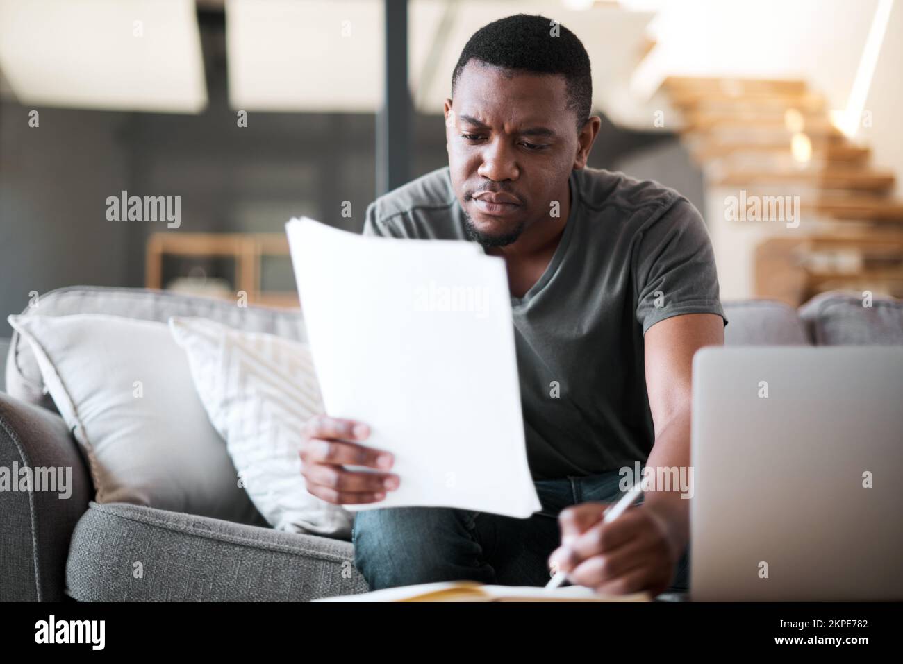 Travail à distance, salon et homme noir avec la paperasserie pour l'assurance, l'investissement de la maison financière. Homme lisant le budget, les taxes et les documents dans un salon Banque D'Images