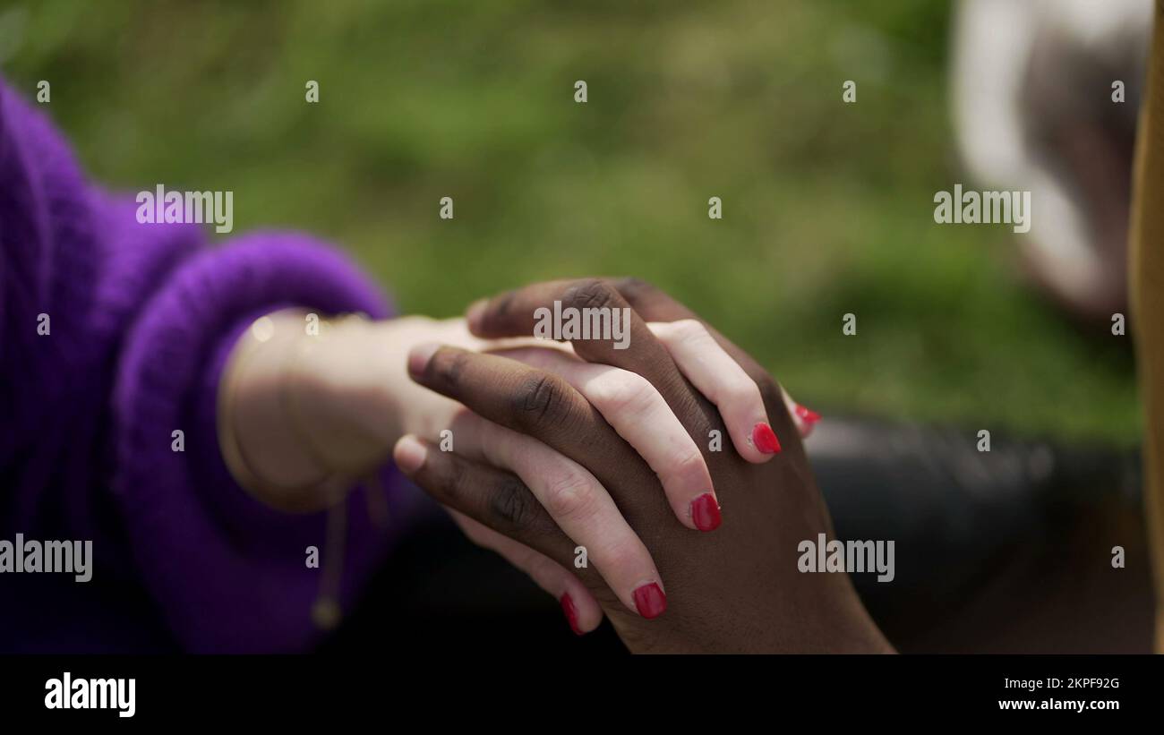 Couple ethniquement diversifié tenant les mains en gros plan. Femme de race mixte et homme noir montrant l'amour et l'affection Banque D'Images