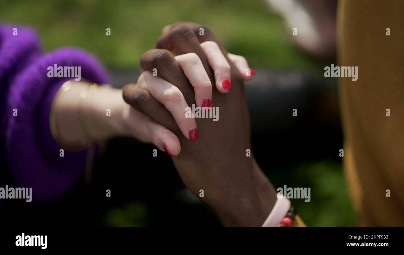 Couple ethniquement diversifié tenant les mains en gros plan. Femme de race mixte et homme noir montrant l'amour et l'affection Banque D'Images