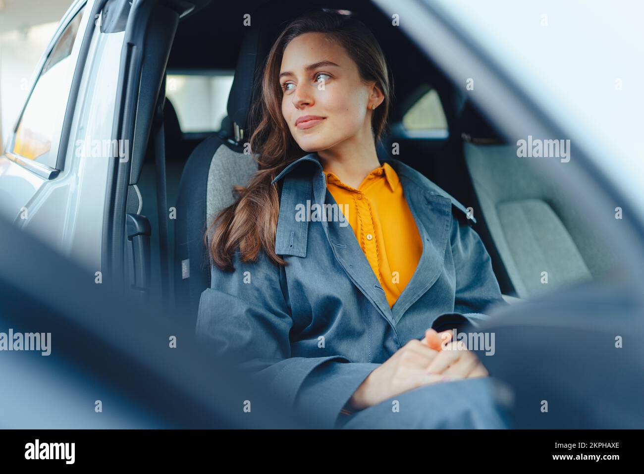 Une jeune femme excitée assise dans sa voiture, attendant quelqu'un. Banque D'Images