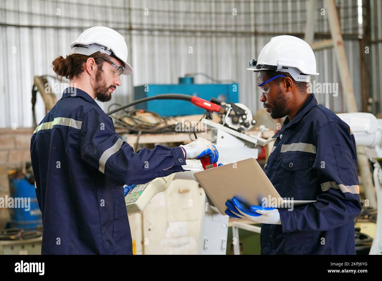 Ingénieur en robotique travaillant à la maintenance du bras robotique moderne dans l'entrepôt de l'usine Banque D'Images