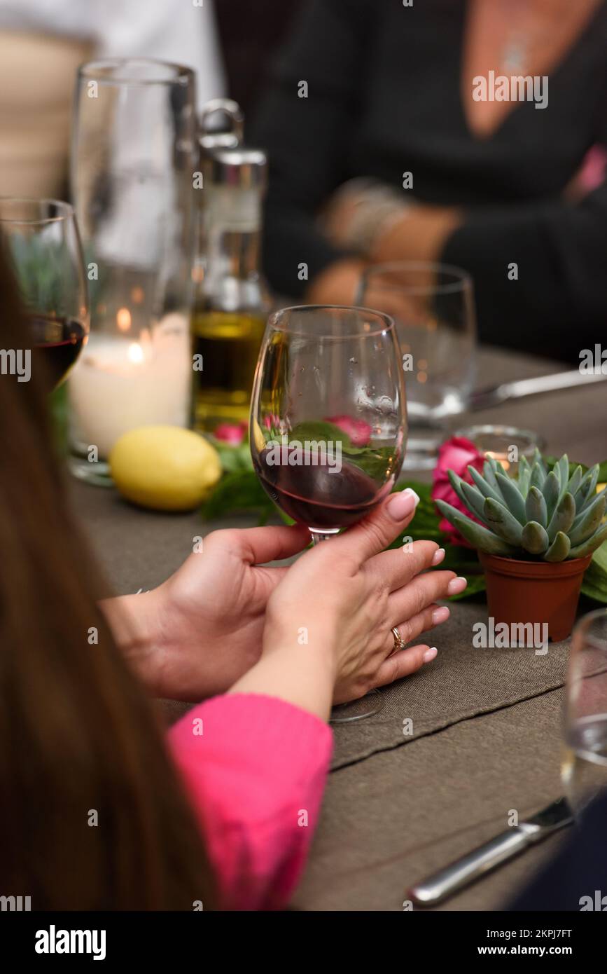 Femme tenant un verre à vin à la table du restaurant Banque D'Images