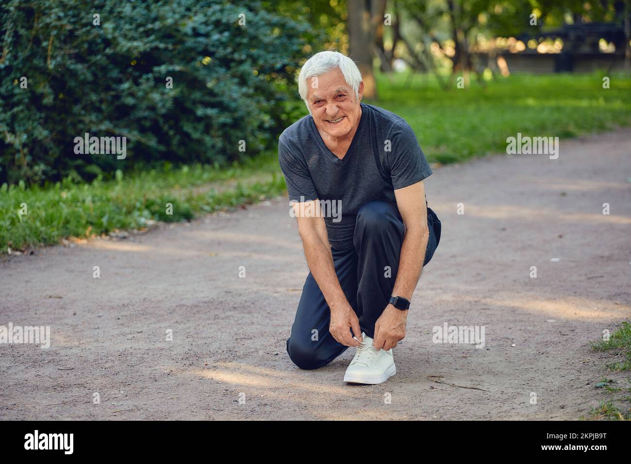 Homme âgé en tenue sportive cravates chaussures prêt pour le jogging matinal ou la marche sportive promenade dans le parc d'été sourire regarder la caméra. Une vie active saine Banque D'Images