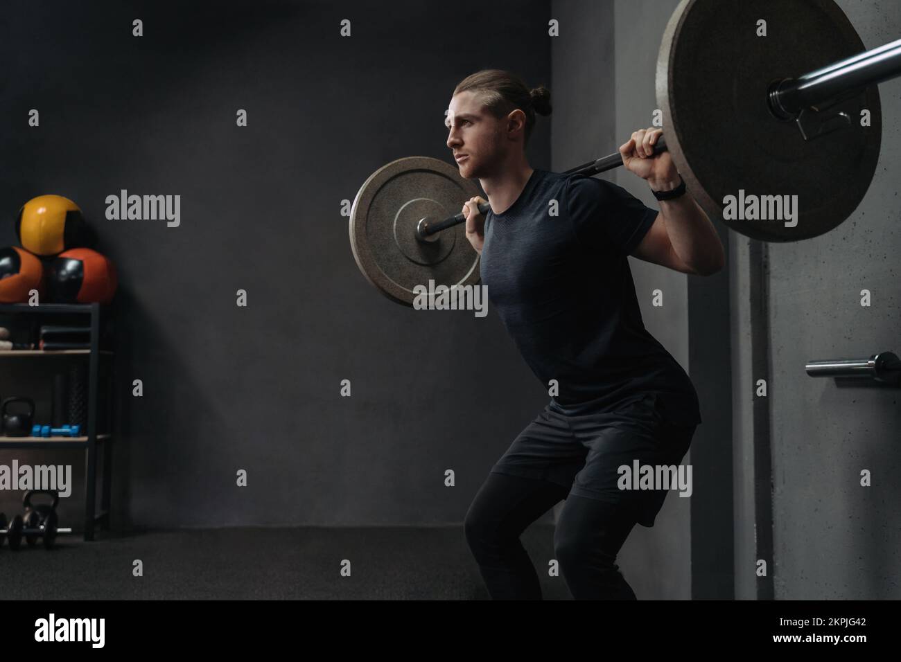 CrossFit athlète levée barbell dans la salle d'entraînement sombre. Concept de formation fonctionnelle et de circuit. Copier l'espace Banque D'Images