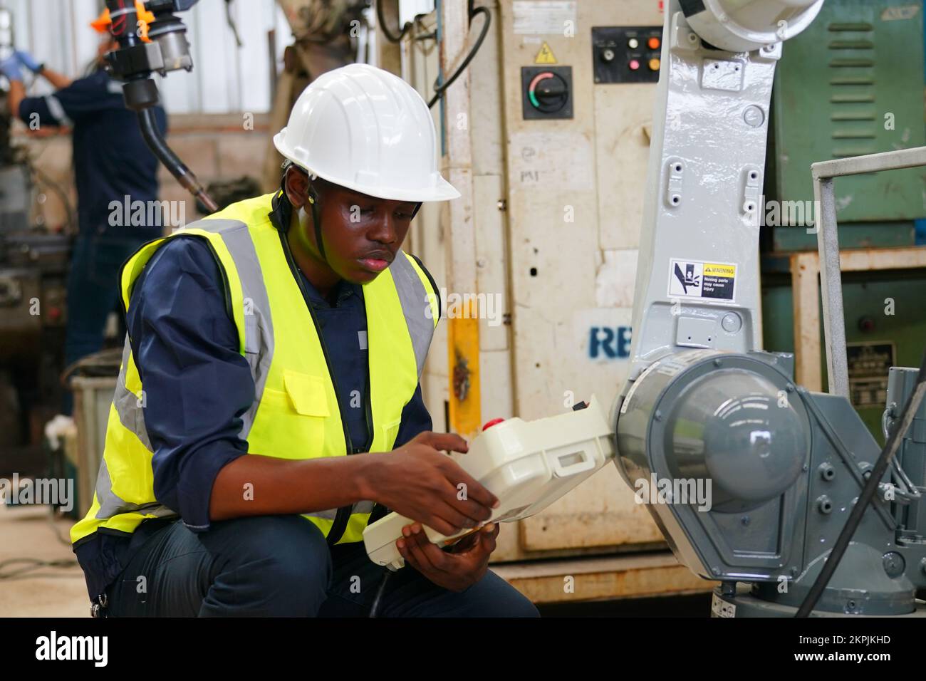 Ingénieur en robotique travaillant à la maintenance du bras robotique moderne dans l'entrepôt de l'usine Banque D'Images