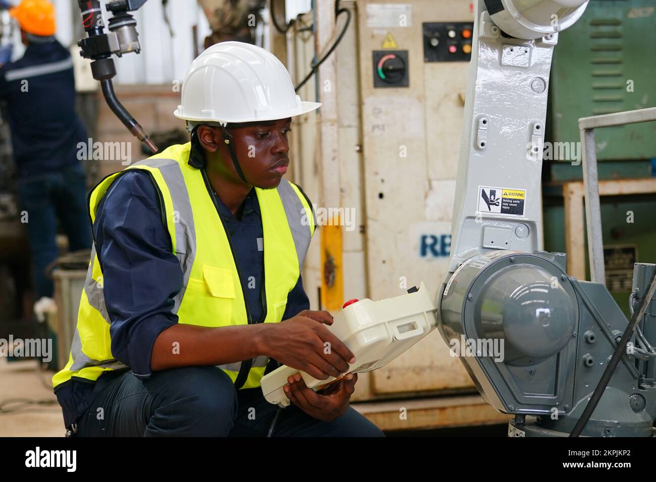 Ingénieur en robotique travaillant à la maintenance du bras robotique moderne dans l'entrepôt de l'usine Banque D'Images