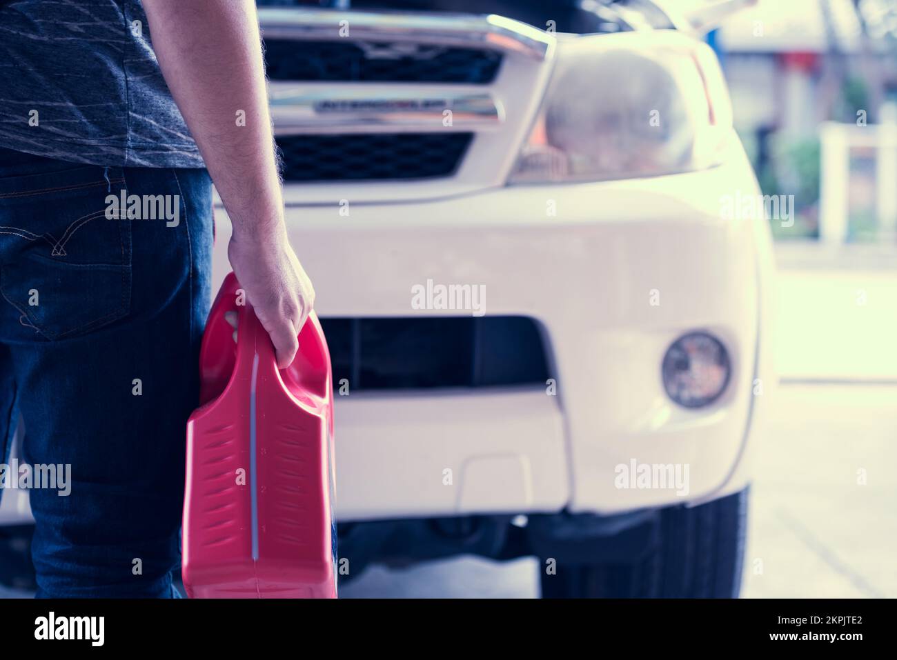 Un technicien en mécanique automobile tient à la main l'huile lubrifiante du moteur, élimine les contaminants en suspension, les boues, ce qui contribue à maintenir le moteur en marche plus propre et en bon état de marche Banque D'Images