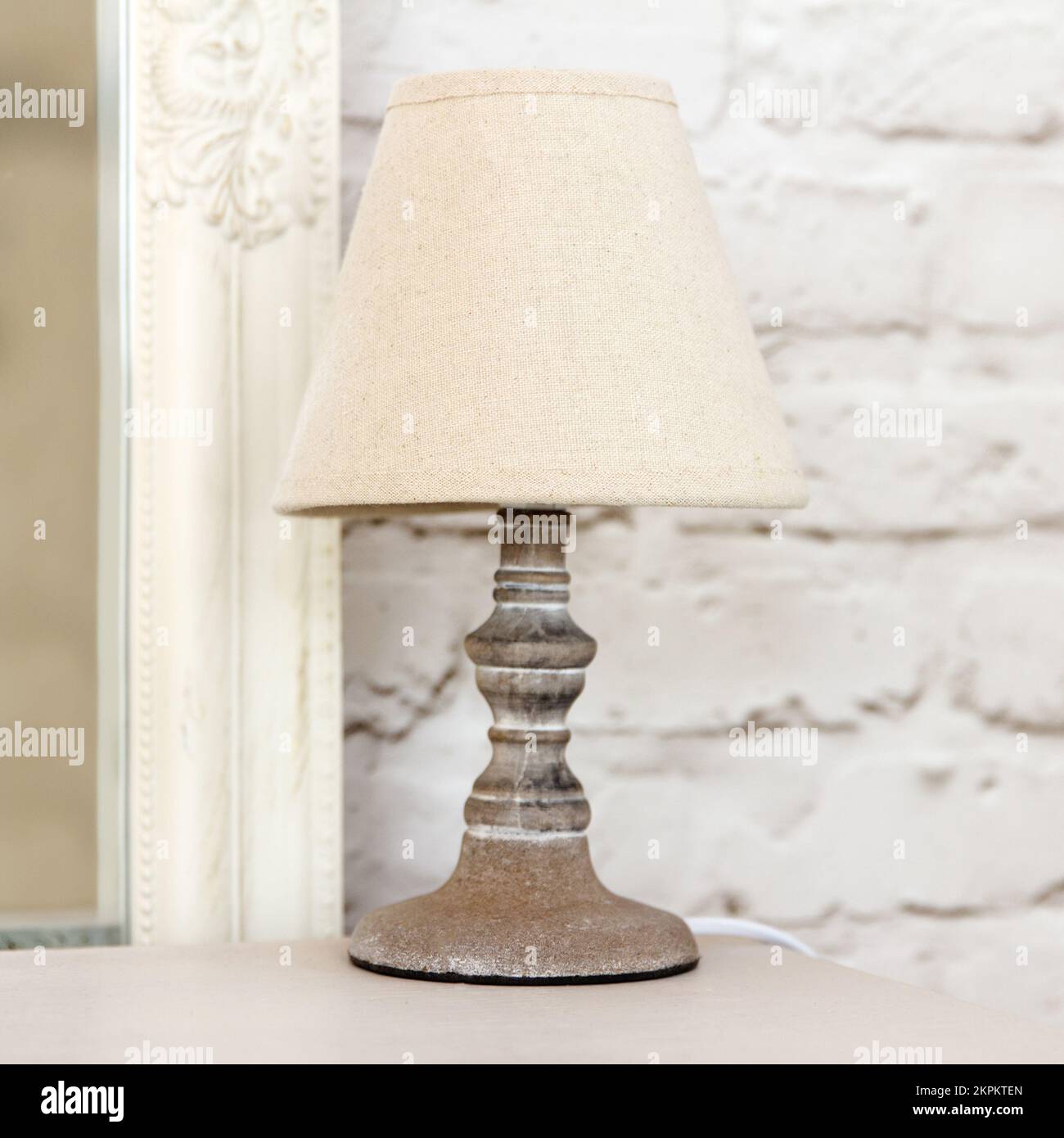 Élégante lampe beige rétro avec porte-couteau décoratif en bois sur table de chevet dans la chambre. Banque D'Images