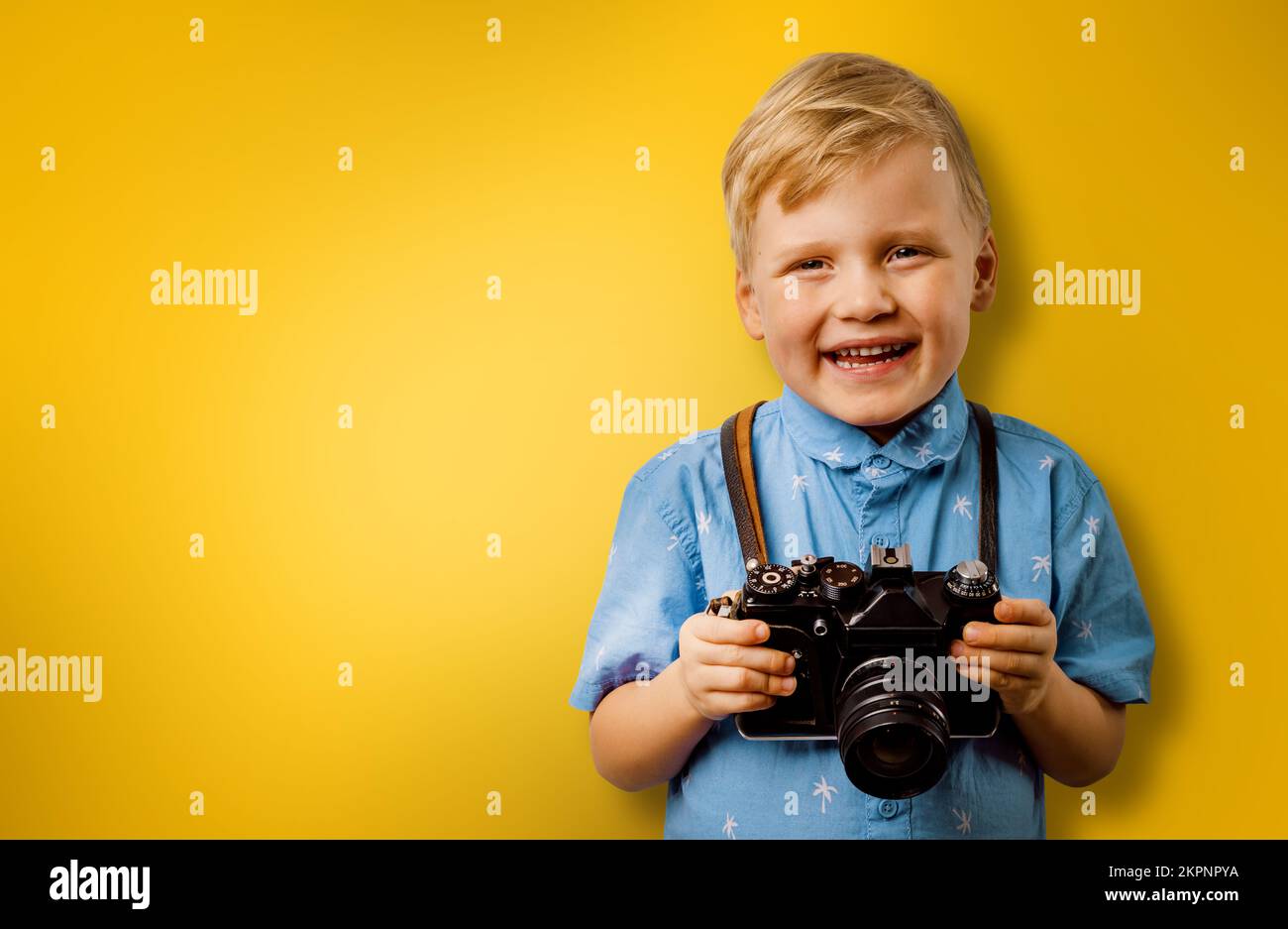 petit garçon souriant avec appareil photo rétro sur fond jaune avec espace de copie. photographe d'enfant Banque D'Images