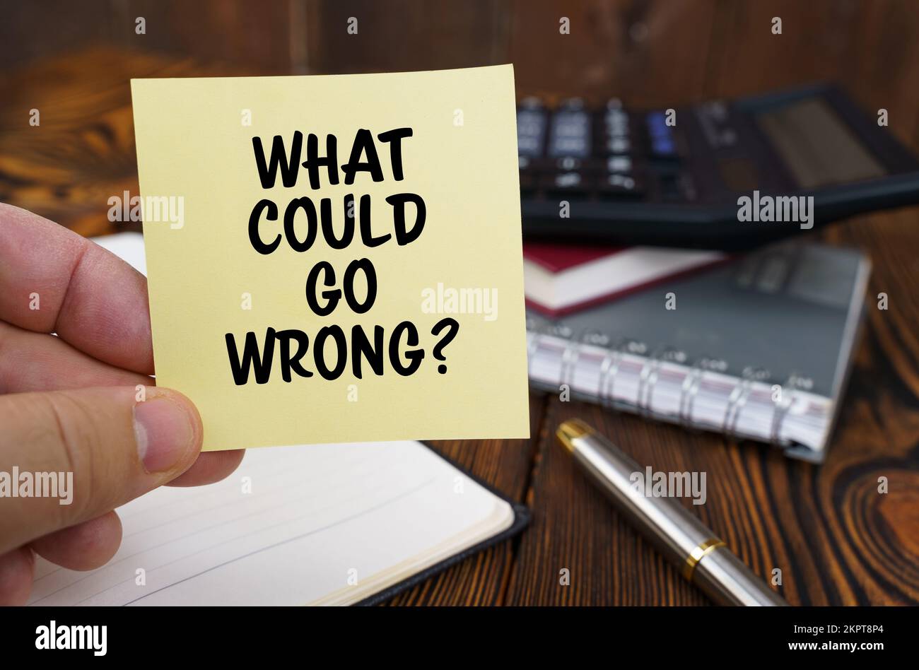 Concept d'entreprise. Dans les mains d'un homme est un autocollant avec l'inscription - ce qui pourrait mal aller. Dans l'arrière-plan dans un arrière-plan flou sont bureau Banque D'Images