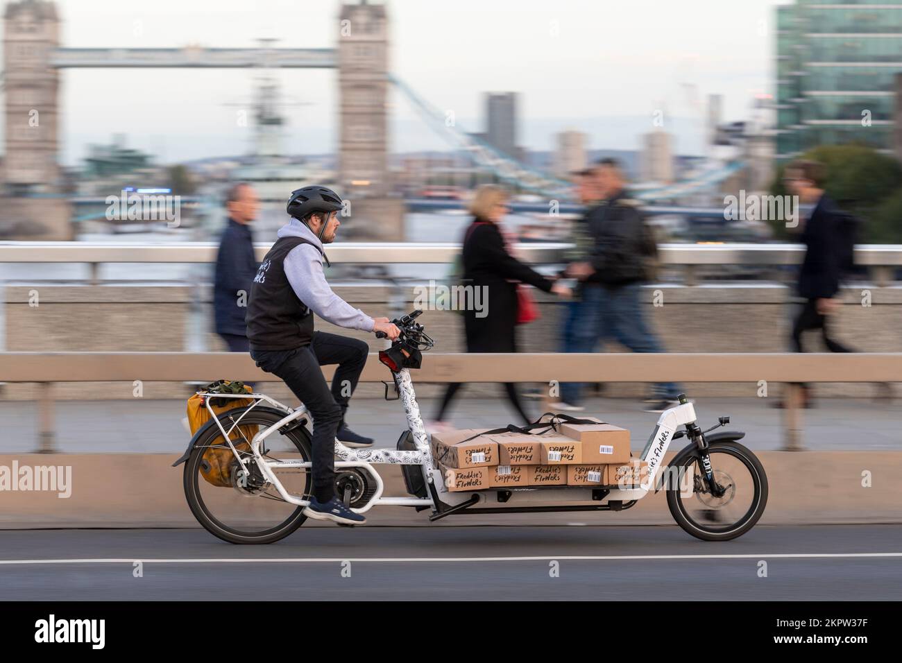 Un coursier de vélo à cheval sur un vélo e-cargo chargé de fleurs à travers, London Bridge, Londres, Royaume-Uni. 18 octobre 2022 Banque D'Images