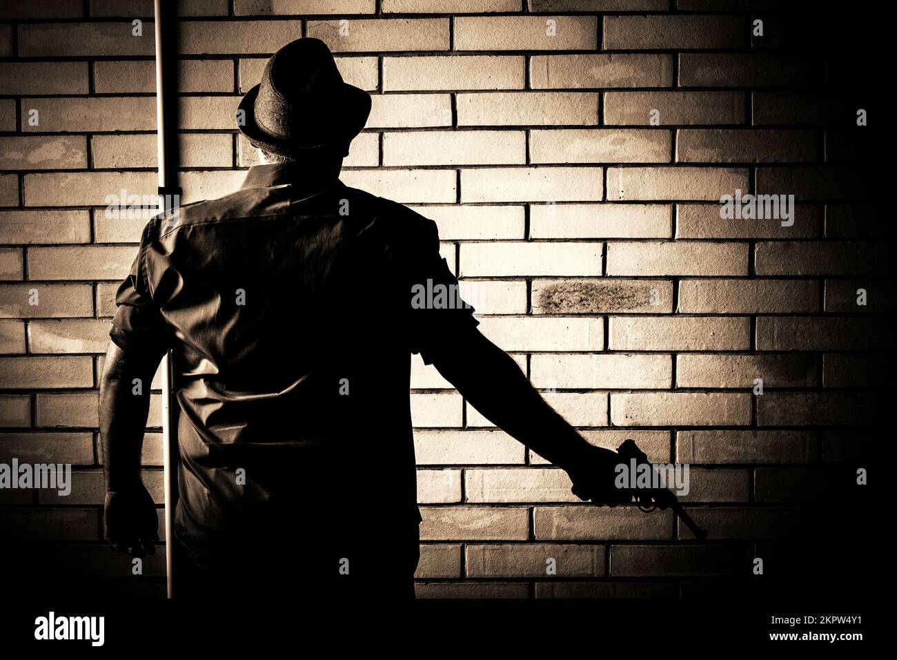 Silhouette sombre de l'arrière-rue d'un agent secret sur le point de se rendre lors de la levée d'une arme de poing dessinée. La tromperie Banque D'Images