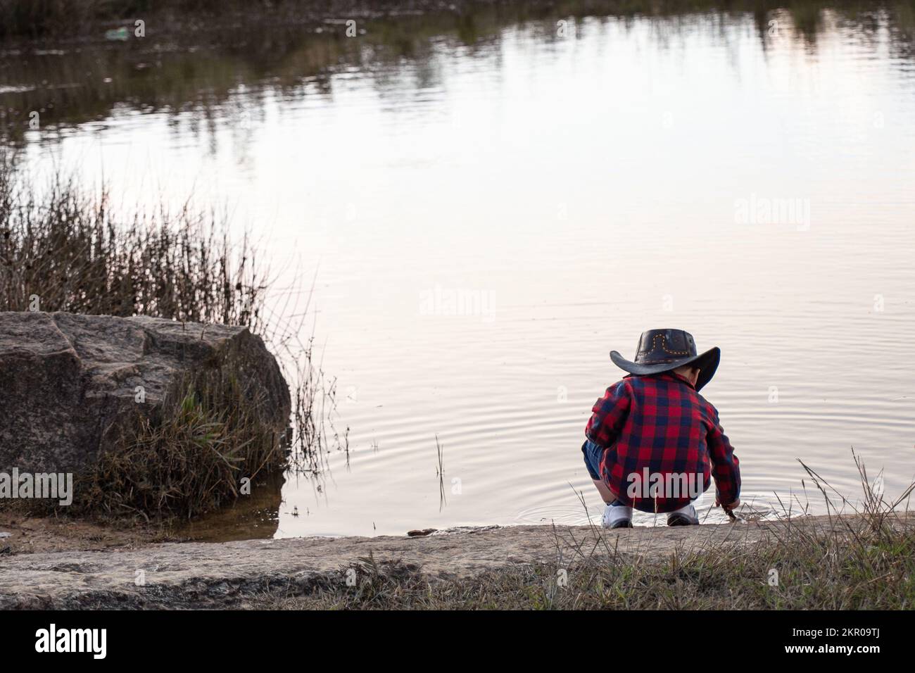 petit garçon paysan avec chapeau jouant dans un lagon Banque D'Images